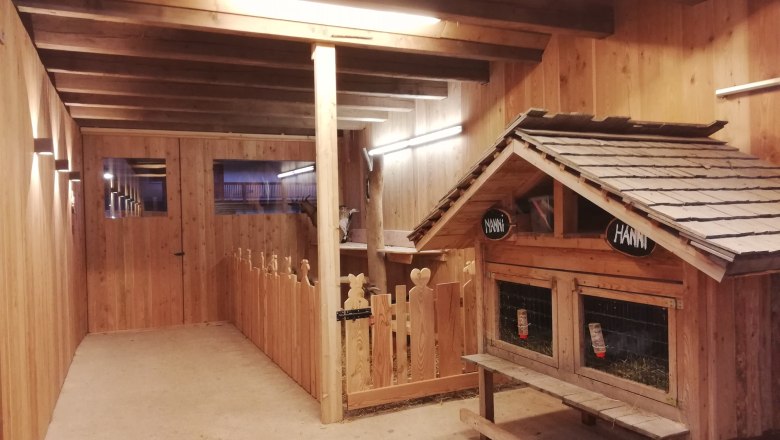 Kecske istálló, © Familie Rosinger Belső nézet egy fából készült kecskeólról, kecsketerítővel és kis házzal.