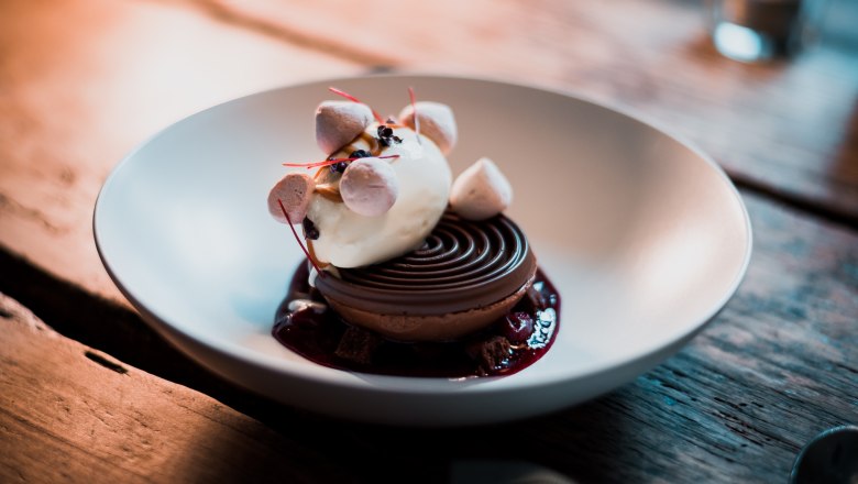 Csokoládé kupola - mousse / brownie / fagylalt / crumble, © Vinzenz Pauli/Philip Hinteregger Fagylaltot, habot és morzsát tartalmazó desszert tálban tálalva.