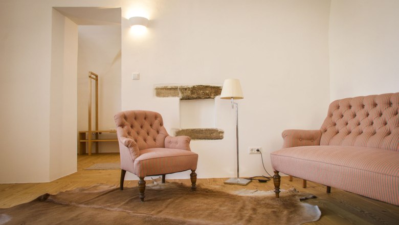 Oberstockstall Estate, © Robert Herbst Hangulatos nappali egy fotel, egy kanapé, egy állólámpa és egy szőnyeg a fapadlón.