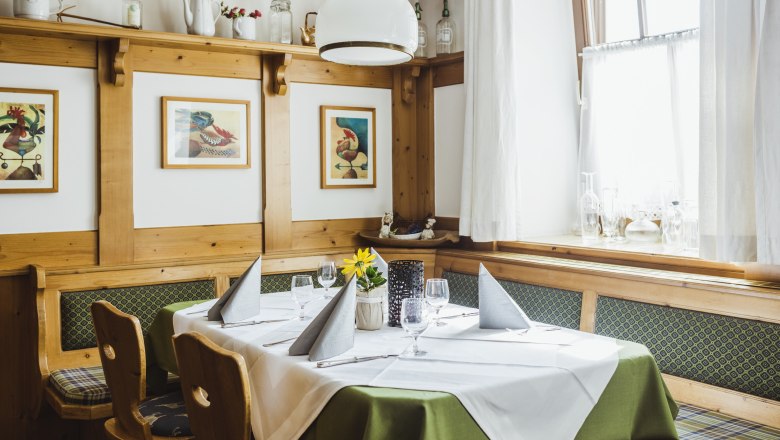 Szalon törzsvendégasztallal, © Niederösterreich Werbung/David Schreiber Hangulatos szalon fabútorokkal, terített asztallal és képekkel a falon.