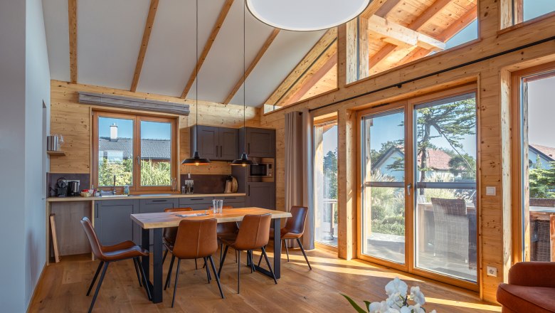 Kittenberger Chalets a Gartensee-nél, © Niederösterreich Werbung / Maximilian Pawlikowsky Egy modern faház belső nézete, fagerendákkal, étkezőasztallal és nagy ablakokkal.