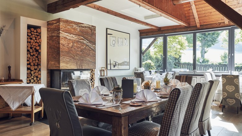 Ízléses környezet, nagy borválaszték, © Niederösterreich Werbung/Andreas Hofer Elegáns étterem fagerendákkal, kandallóval és terített asztalokkal.