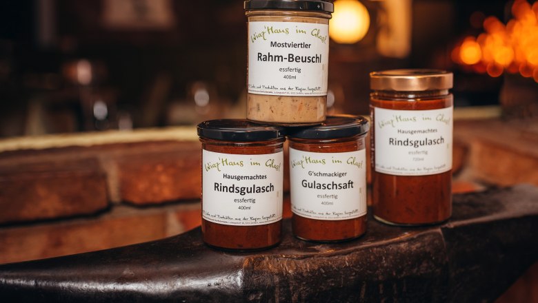 Pub az Ön otthonában, © Niederösterreich Werbung/Daniela Führer Három üveg készétel egy üllőn, "Wirtshaus im Glas" felirattal.