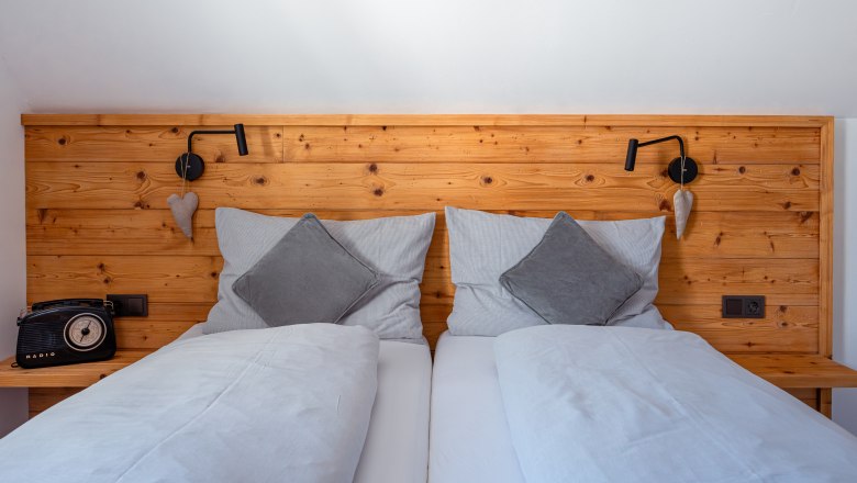 Leopold an der Ybbs, © © Niederösterreich Werbung/ Maximilian Pawlikowsky Hangulatos franciaágy, fából készült háttámlával, szürke párnákkal és takarókkal. Balra retro rádió, jobbra olvasólámpa és szívdíszítés.