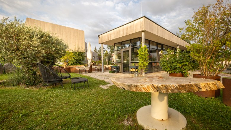 Naturhotel Gut Guntrams Gartenlofts kertészlakások, © Niederösterreich Werbung / Maximilian Pawlikowsky Egy modern szálloda kerthelyisége ülőhelyekkel és növényekkel.