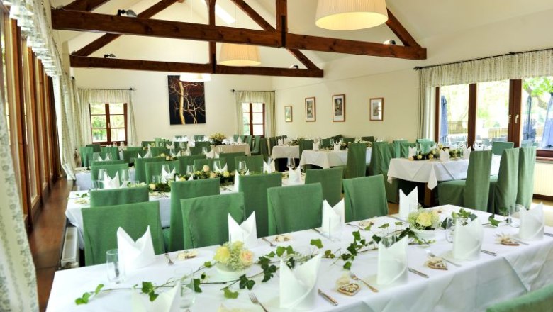 Kolostorszálló Thallern, © Klostergasthaus Thallern Egy ünnepi díszítésű fogadó belső nézete, zöld székekkel és fagerendákkal.