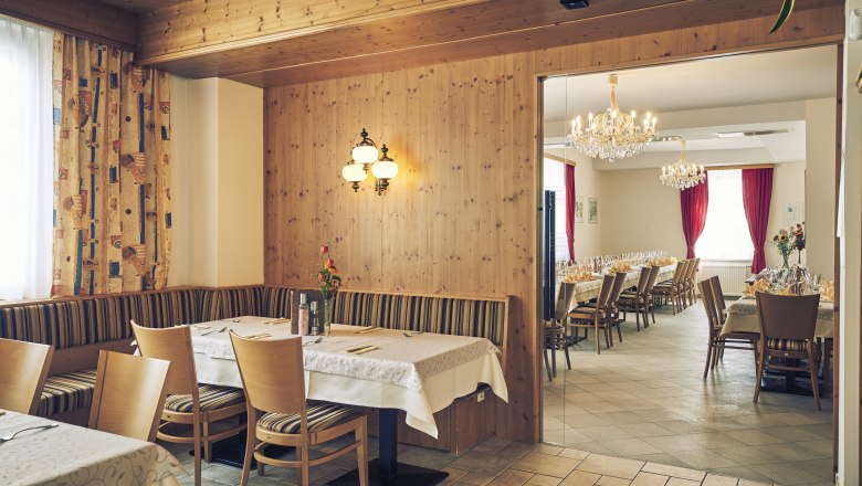 Vendégszoba és bankettterem, © Niederösterreich Werbung/Andreas Hofer Hangulatos vendégszoba fából készült falakkal és egy szomszédos díszteremmel, csillárokkal és terített asztalokkal.