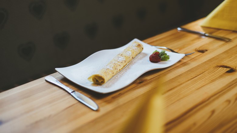 Édes desszert: egy palacsinta mindig elfér a hasadban, © Niederösterreich Werbung/David Schreiber Egy palacsinta fehér tányéron, eperrel és mentával, faasztalon tálalva.