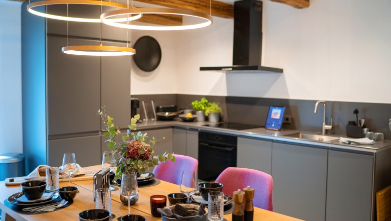 Csodákkal teli faházak és helyek - Weidehaus De Luxe, © WUNDERVOLL eben Modern konyha négyszemélyes étkezőasztallal és stílusos világítással.