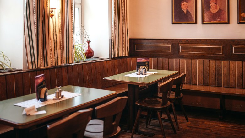 Hagyományos szalon a Zwettl-i Dreifaltigkeitsplatz-on, © Niederösterreich Werbung/Daniela Führer Hagyományos szalon fából készült bútorokkal és festményekkel a falon.