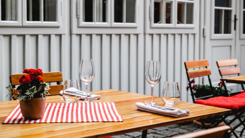 Vendégkert a nyári napokra, © Niederösterreich Werbung/David Schreiber Fából készült asztal kint virágokkal és poharakkal.