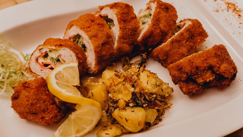 Töltött sült pulyka filé, © Niederösterreich Werbung/Klaus Engelmayer Töltött, sült pulykafilé burgonya körettel és citromszeletekkel fehér tányéron.