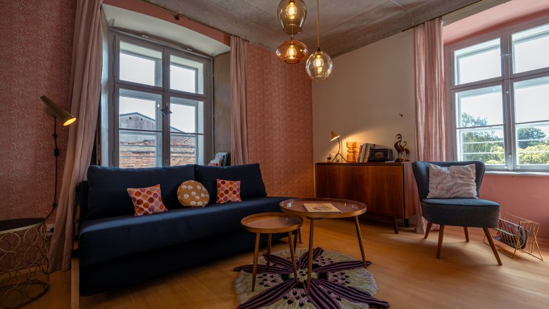 SONNENTOR City Lofts, © Niederösterreich Werbung / Maximilian Pawlikowsky Hangulatos nappali kanapéval, fotelekkel, szőnyeggel és függőlámpákkal.