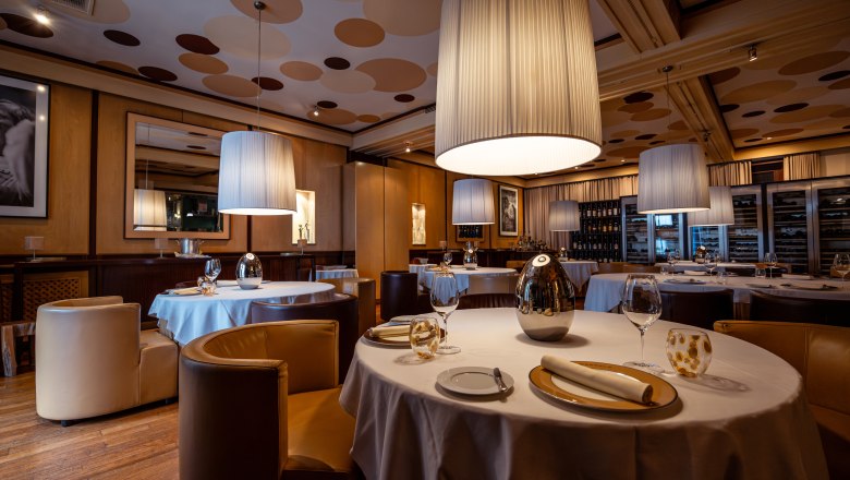 Relais & Chateaux MÖRWALD Hotel am Wagram, © Niederösterreich Werbung / Maximilian Pawlikowsky Elegáns étterem kerek asztalokkal, fehér abrosszal és nagy, lógó lámpákkal.