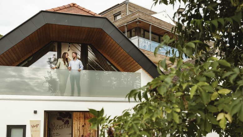 Pincészet Hagn Kellerstöckl, © Weinviertel Tourismus GmbH Modern épület, párral az erkélyen, fákkal körülvéve.