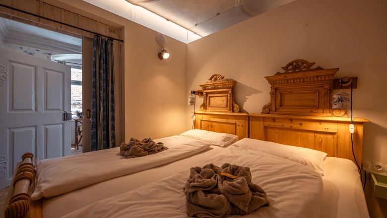 SONNENTOR City Lofts, © Niederösterreich Werbung / Maximilian Pawlikowsky Hangulatos hálószoba két egyszemélyes ággyal és fa dekorációval, meleg megvilágítással.