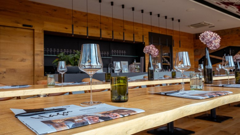 Bor domicile Hagn, © Niederösterreich Werbung / Maximilian Pawlikowsky Egy modern borozó belső nézete terített asztalokkal, borospoharakkal és dekorációval.