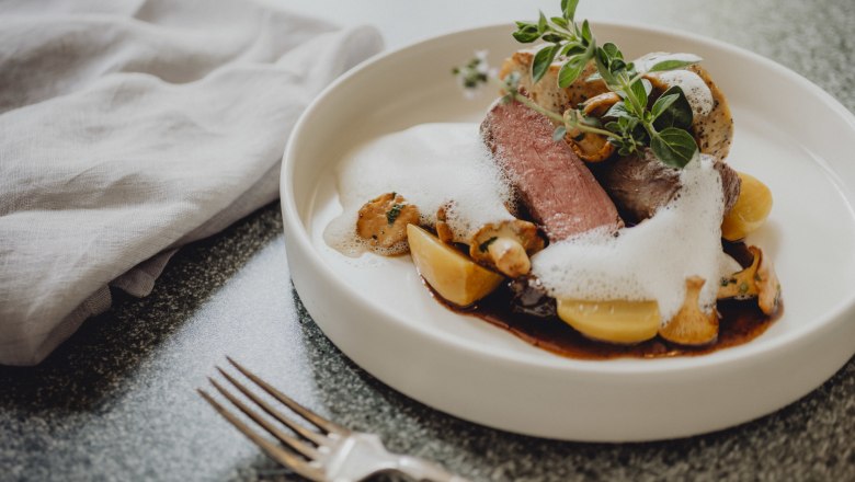 Kétféle saßwaldi szarvashús, mákos szalvétagombóc, © Niederösterreich Werbung/Rita Newman Ínyenc tál szarvashússal, szalvétagombóccal, gombával és habbal fehér tányéron.