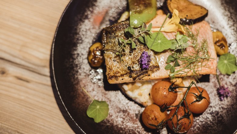 Lazacpisztráng filé zöldséges rizottón, zöldséges rizottóval, © Niederösterreich Werbung/David Schreiber Lazacpisztrángfilé grammel rizottó tányéron zöldségekkel és fűszernövényekkel.