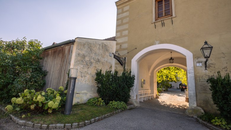 Oberstockstall Estate, © Niederösterreich Werbung / Maximilian Pawlikowsky Az Oberstockstall Estate bejárati kapuja növényekkel és lámpával.