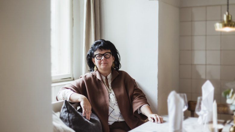 Sandra Blauensteiner háziasszony, © Niederösterreich Werbung/David Schreiber Nő ül egy megterített asztalnál egy hangulatos szobában.