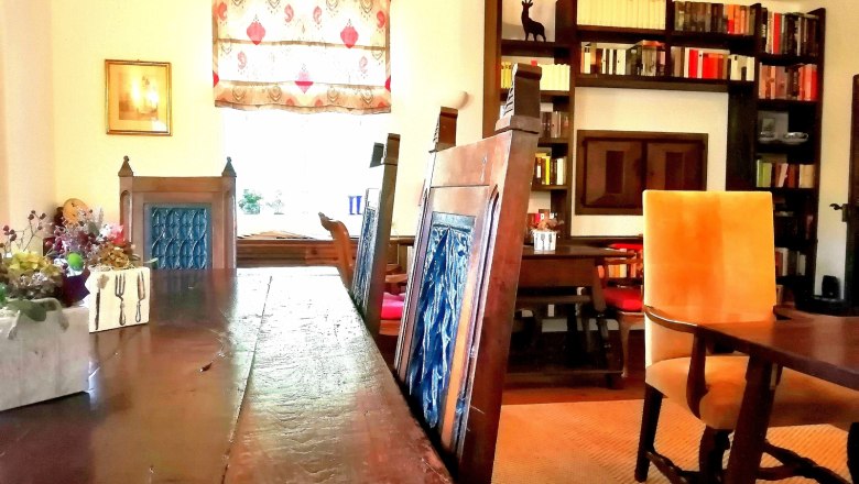 Reggelizőterem, © Landsitz Oberhof Hangulatos reggelizőszoba fa asztallal, kék székekkel, könyvespolccal és dekoratív ablakkal.