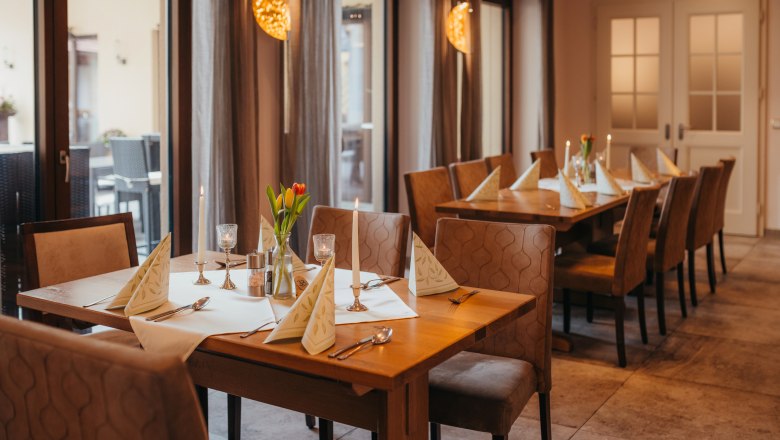 Pub kabaré estekkel és reggeli korsóval, © Niederösterreich Werbung/Daniela Führer Egy hangulatos asztal egy kocsmában, gyertyákkal és virágokkal.