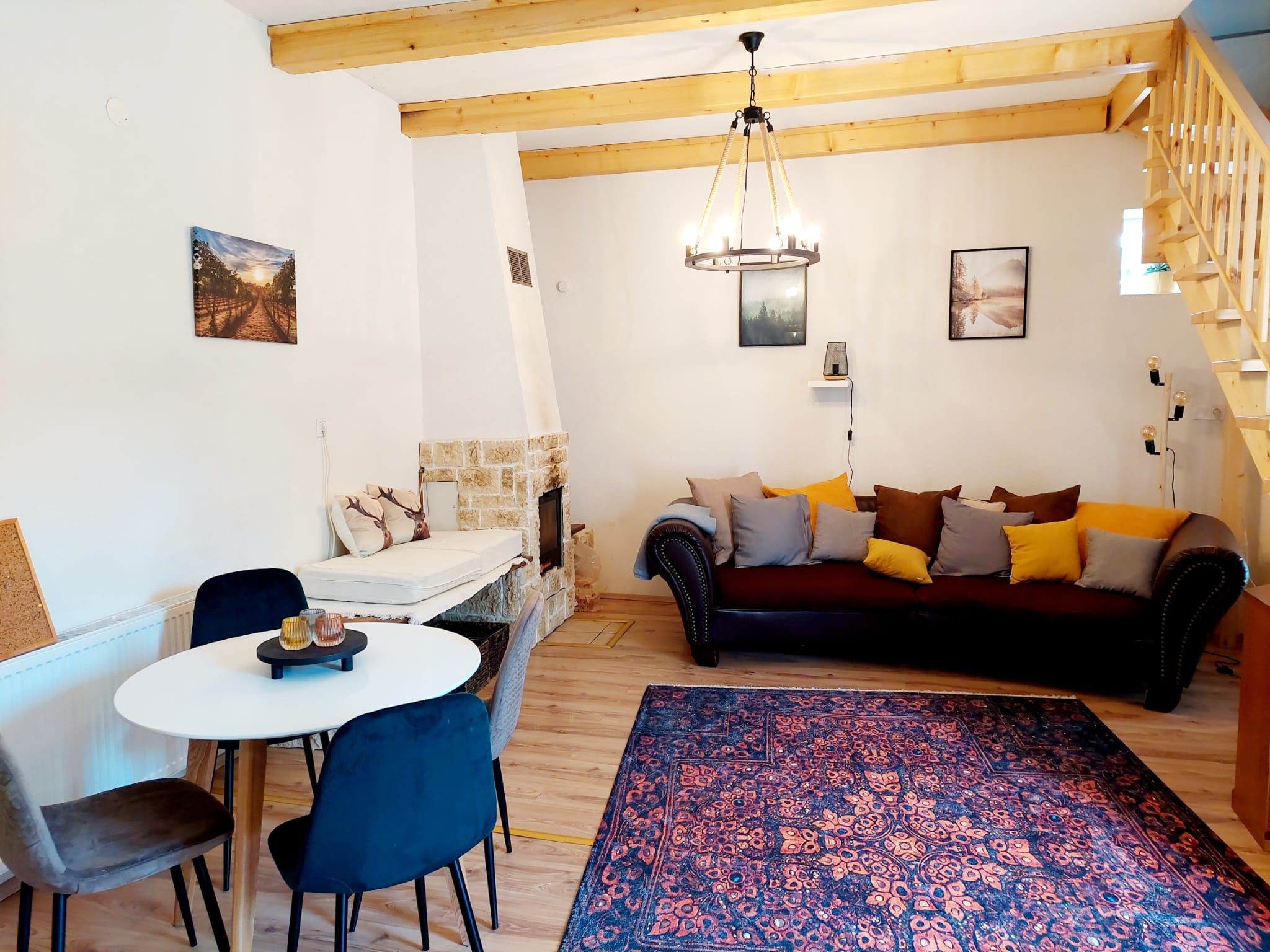 Hangulatos nappali/étkező fagerendákkal, kanapéval, étkezőasztallal és kandallóval.