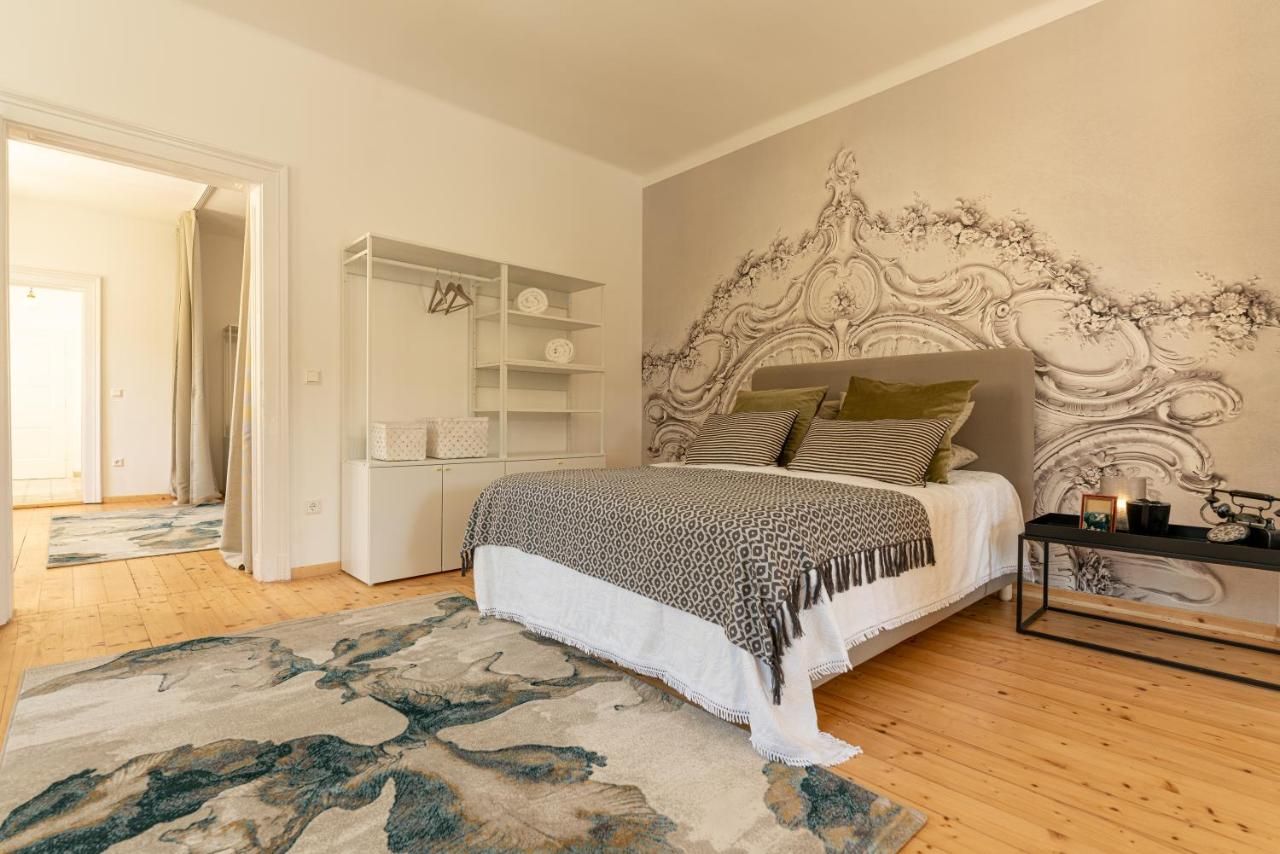 Stílusosan berendezett hálószoba nagy ággyal, díszpárnákkal, szőnyeggel és művészi faldizájnnal.