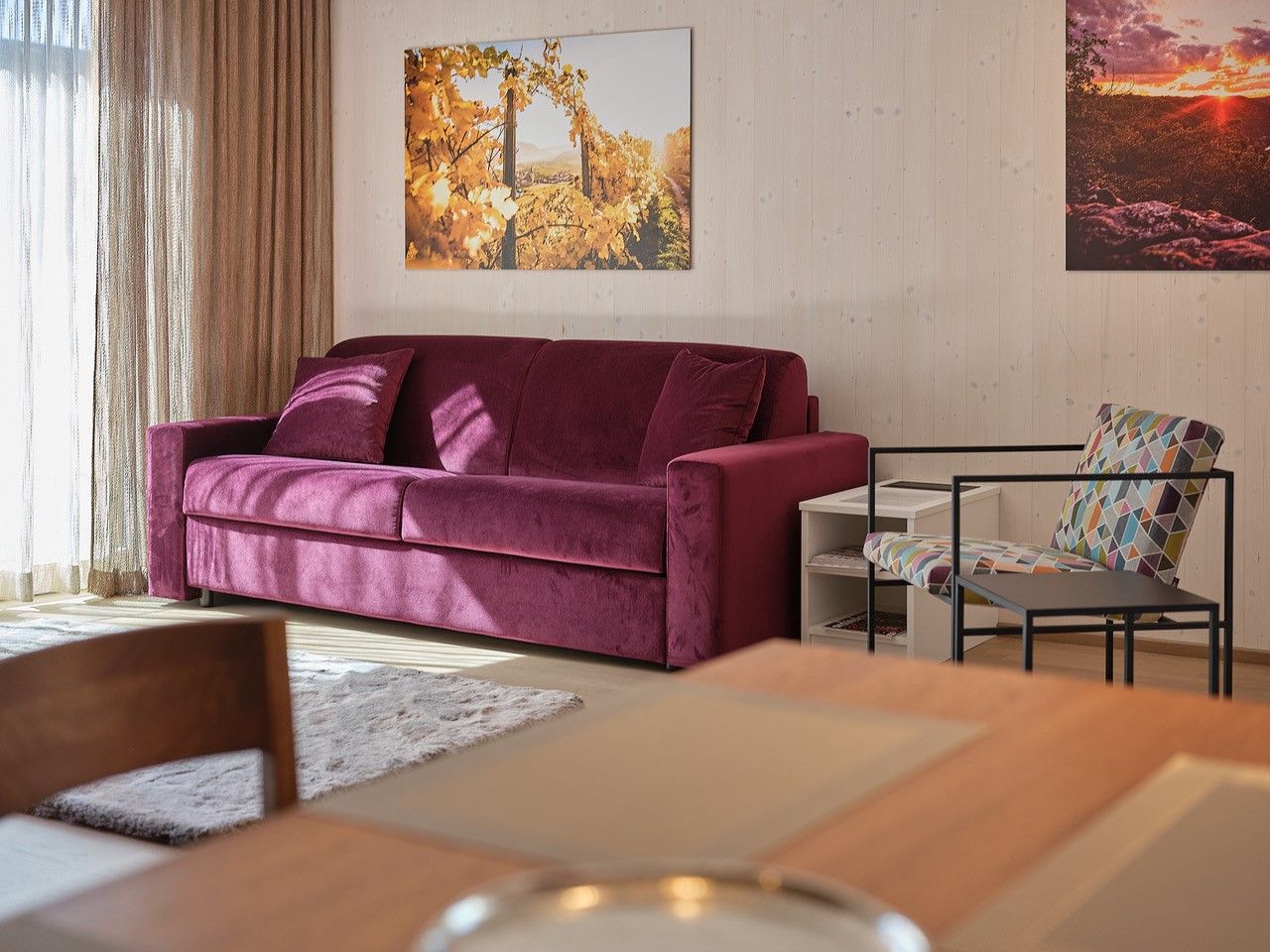 Nappali lila kanapéval, színes székkel és falfestményekkel.