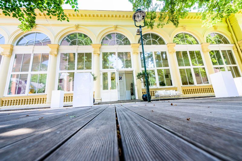 A Kursalon Mödling külső nézete nagy ablakokkal és fapadlóval.