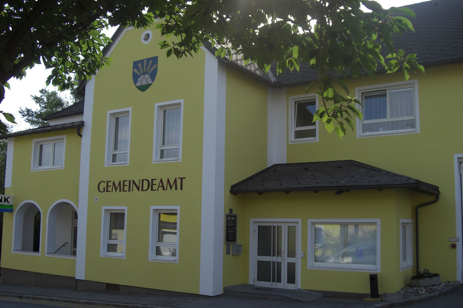 Sárga színű épület "GEMEINDEAMT" felirattal és felette címerrel.