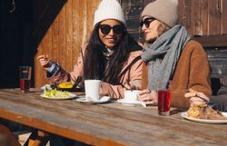 Két sífutó egy hóval borított pályán egy téli hegyvidéki tájban.