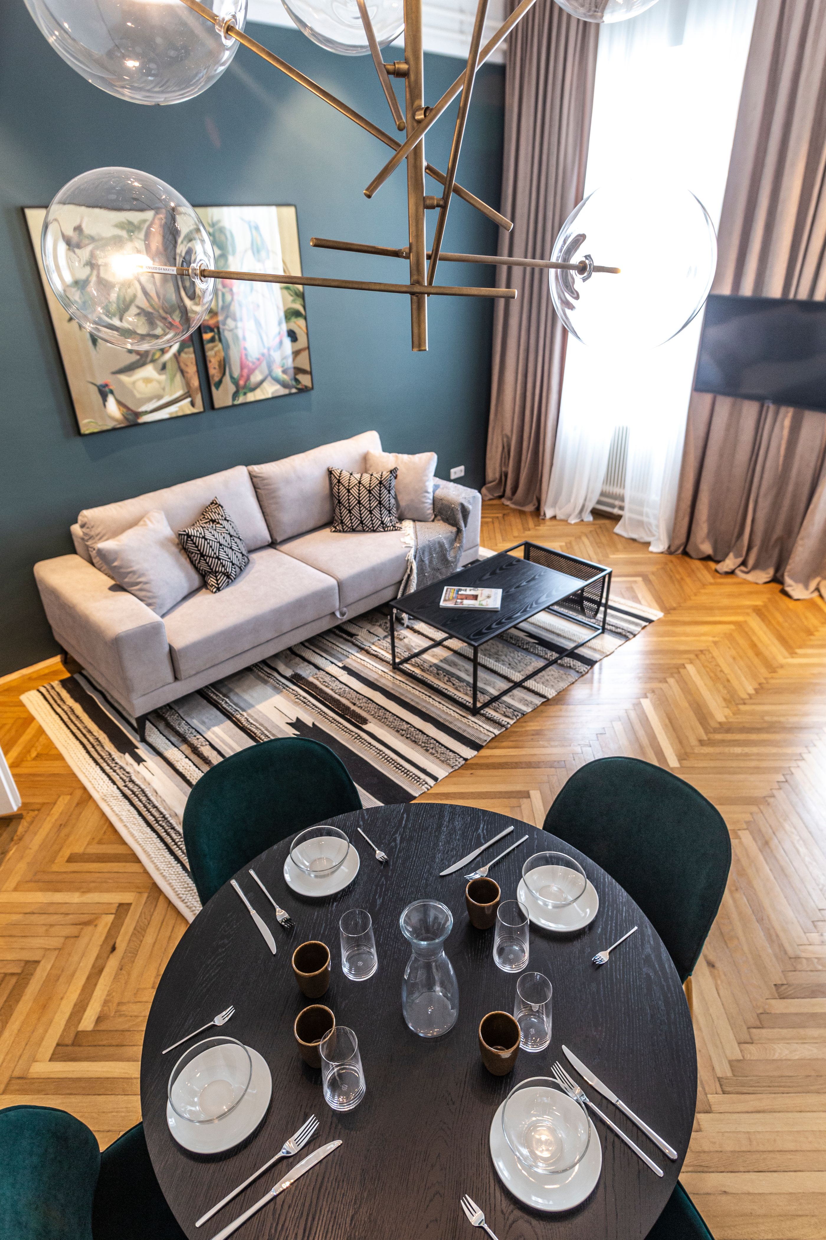 Modern nappali kanapéval, dohányzóasztallal, szőnyeggel és étkezőasztallal terítékkel.