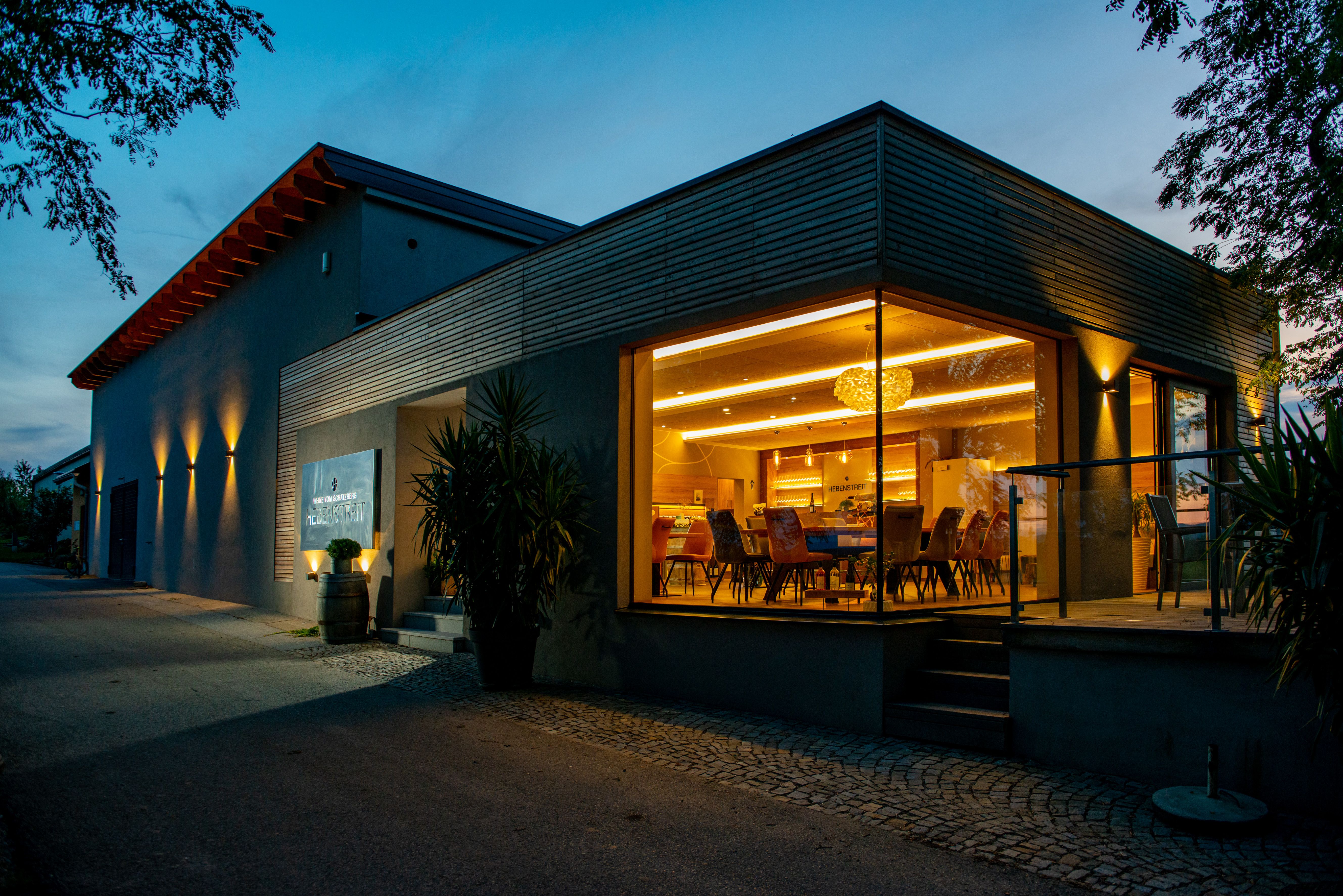 Modern épület üveghomlokzattal és belső világítással alkonyatkor.