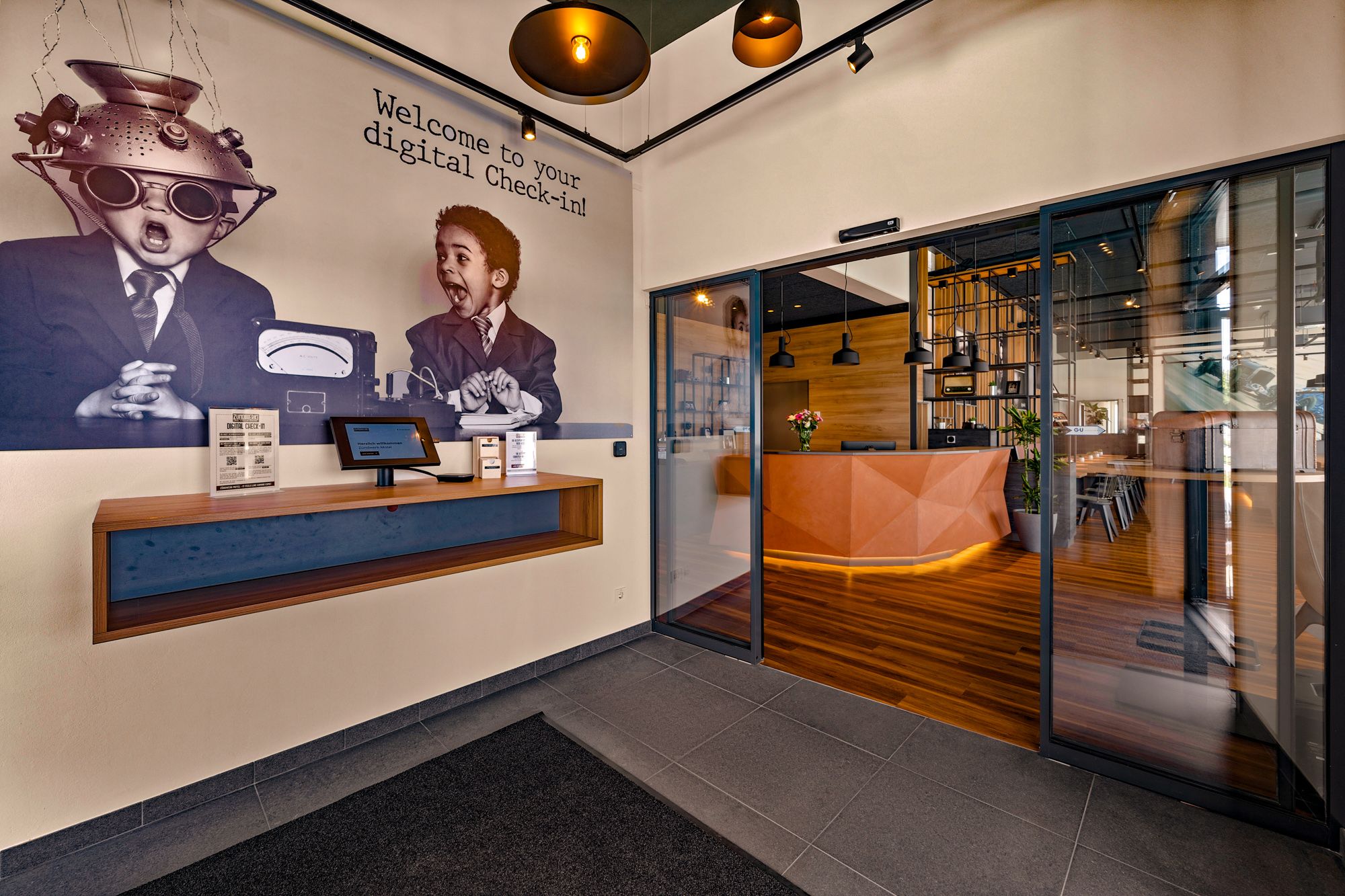 Egy modern motel bejárata digitális bejelentkezéssel és stílusos recepcióval.