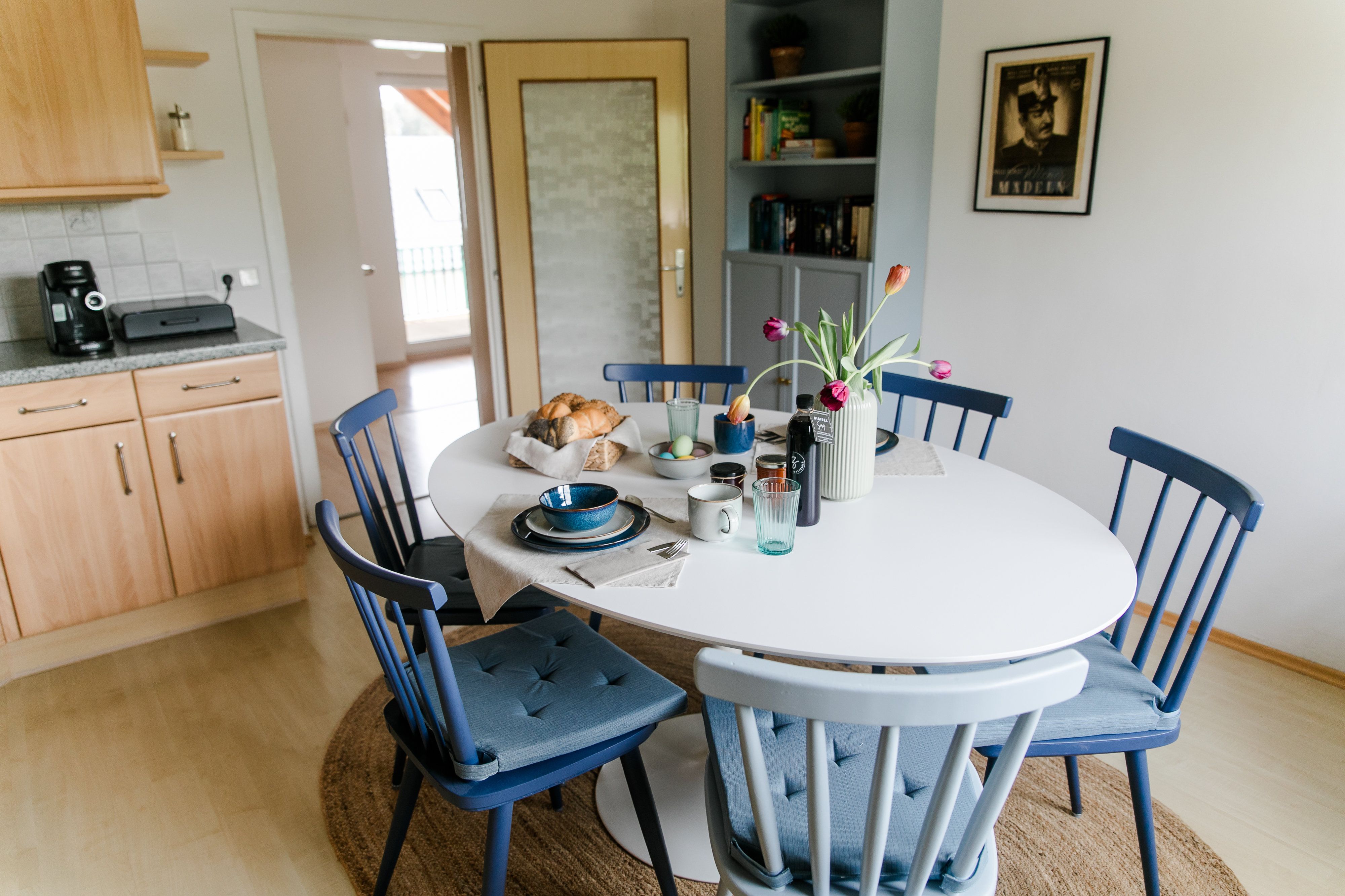 Étkező a konyhában kerek asztallal, kék székekkel és reggelizőasztallal.