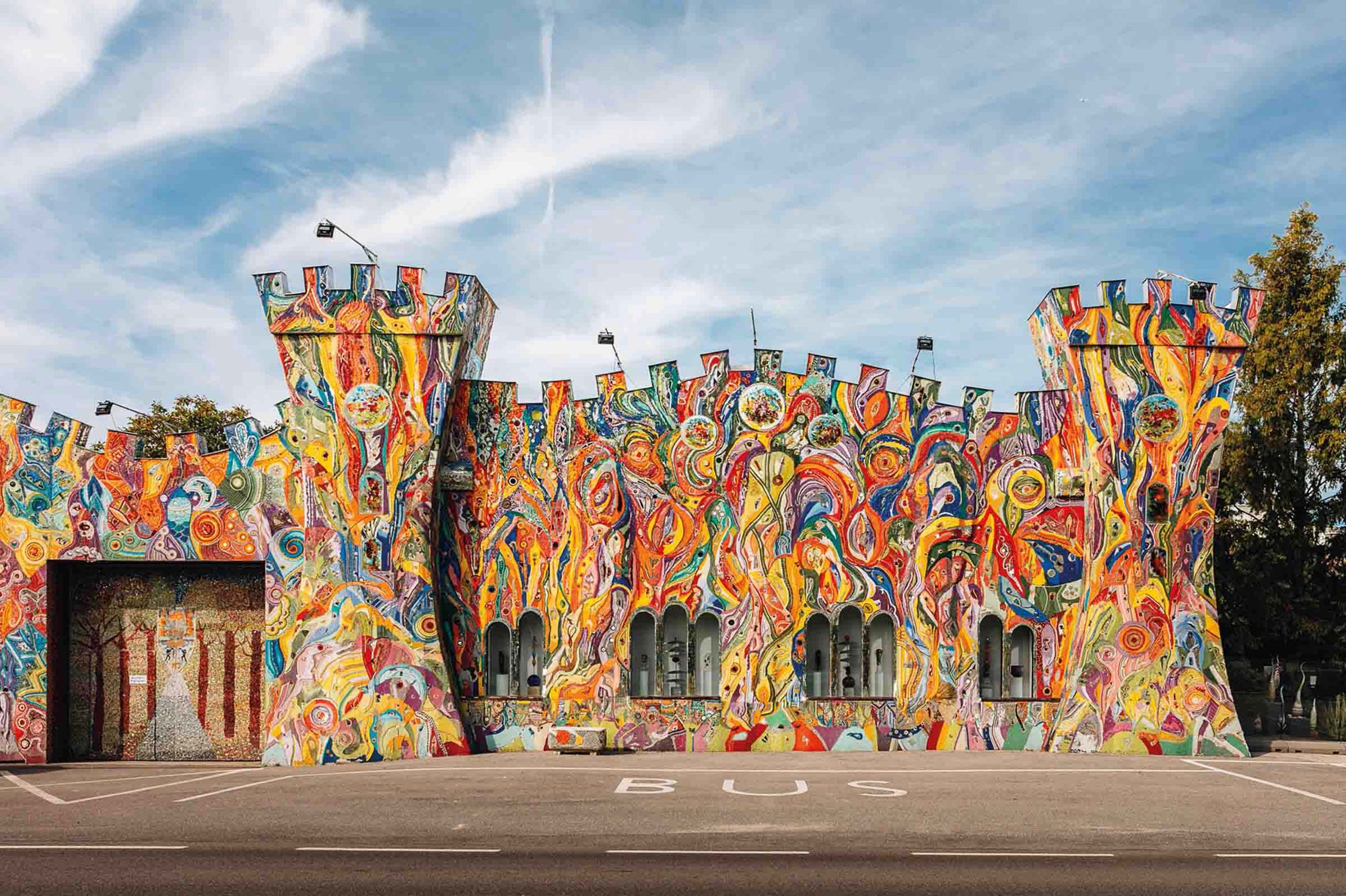 Színesen festett, tornyos kastély alakú épület homlokzata.