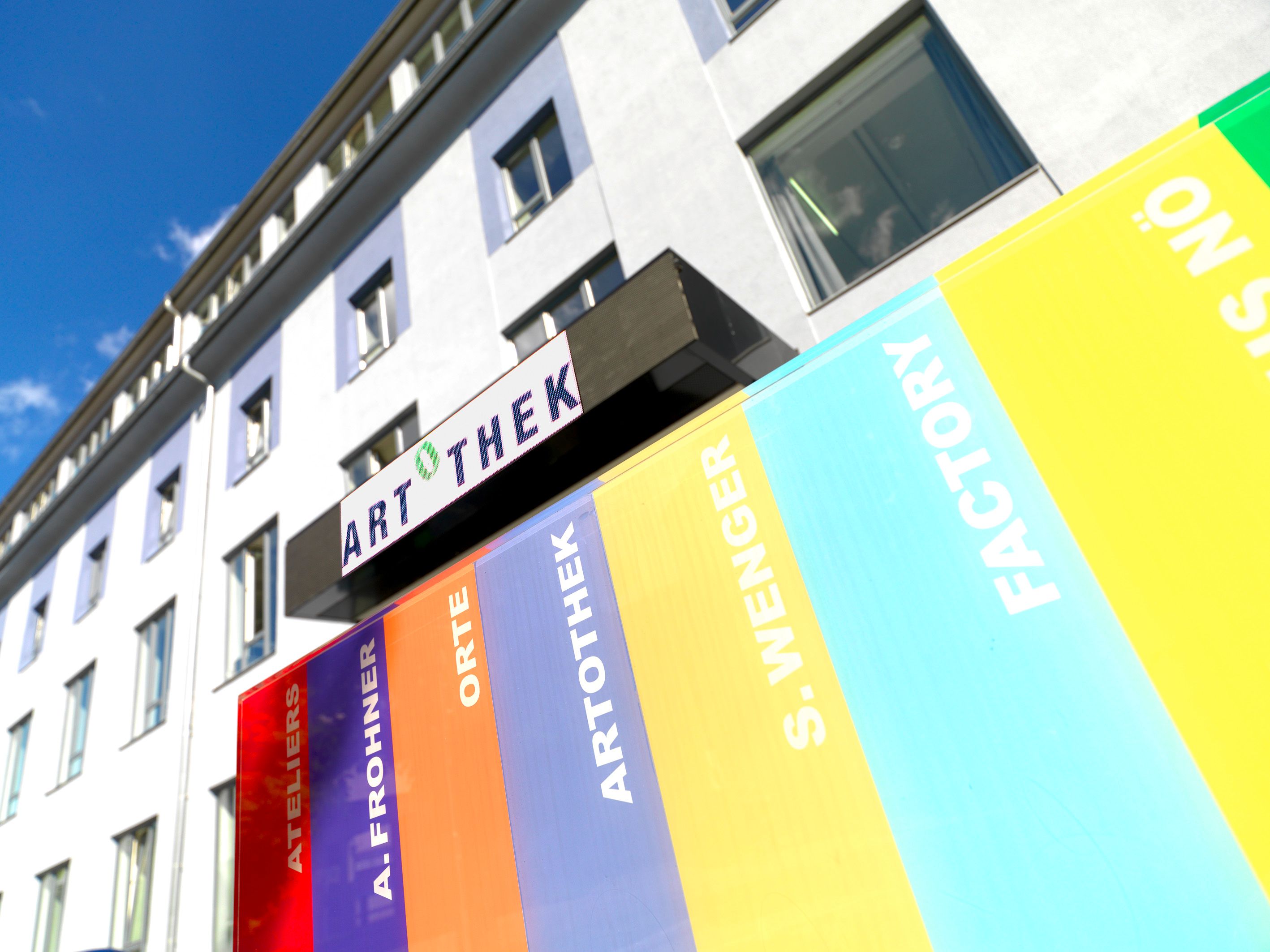 Egy épület külső nézete Artothek felirattal és színes csíkokkal.