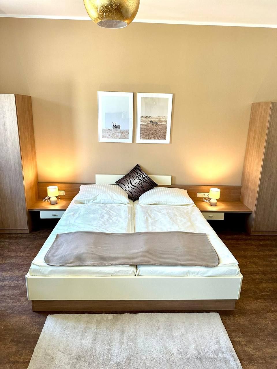 Modern hálószoba franciaággyal, két éjjeliszekrénnyel és falfestményekkel.