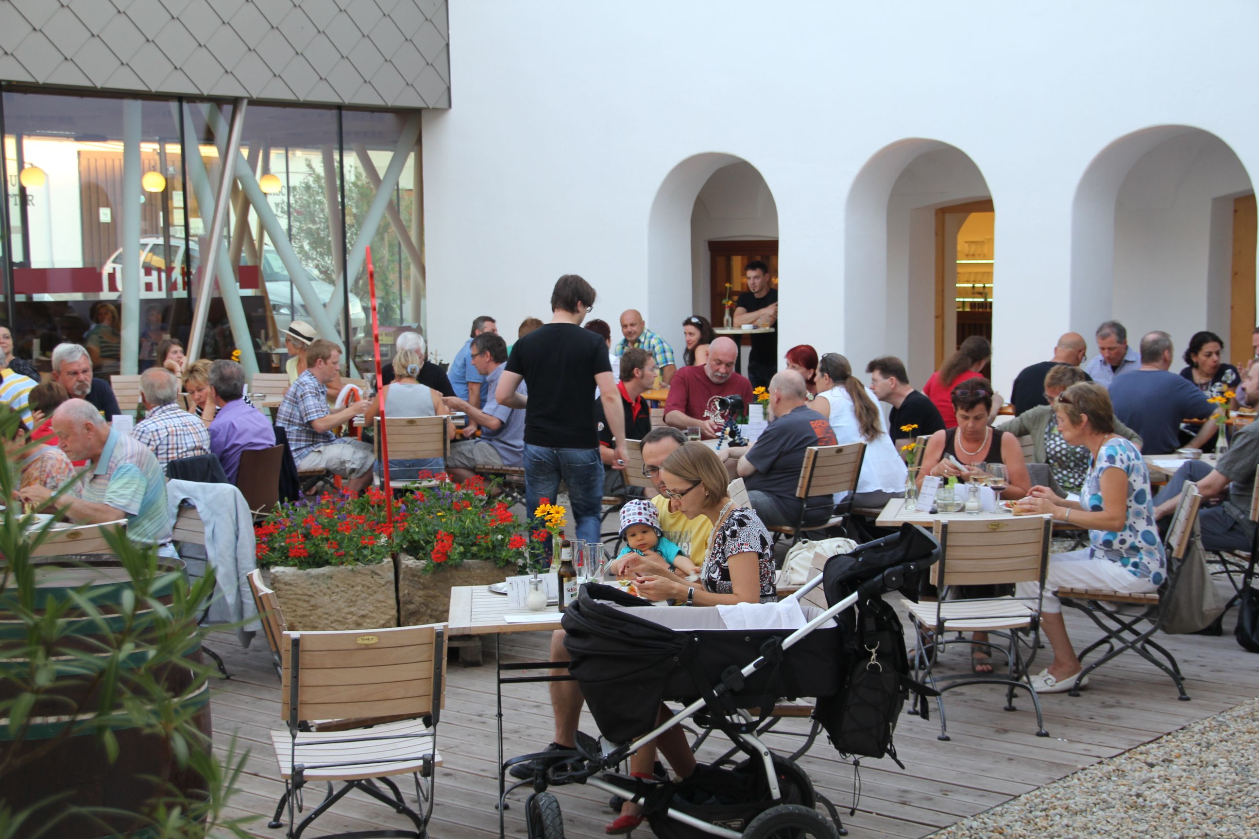 Az emberek egy belső udvaron asztaloknál ülnek és esznek.