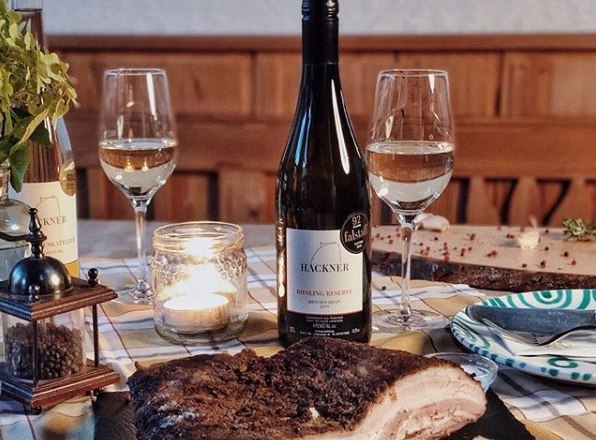 Asztal boros&uuml;veggel, k&eacute;t poh&aacute;rral, gyerty&aacute;val &eacute;s h&uacute;st&aacute;llal.