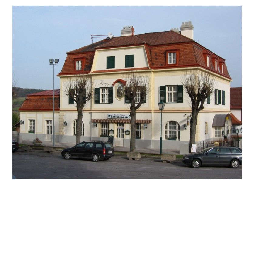Egy kétszintes épület, piros tetőcseréppel és zöld redőnyökkel, a Bärenschlössl panzió felirattal.