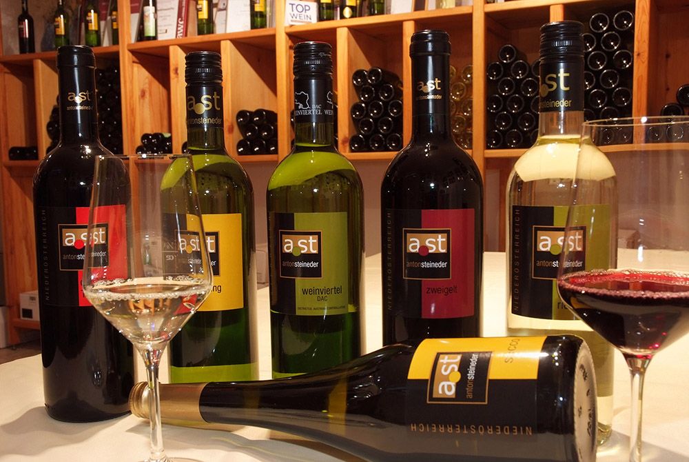 Különböző borosüvegek és poharak egy asztalon egy borospincében.