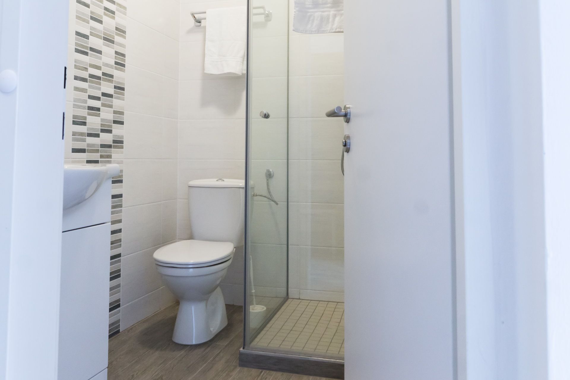 Modern fürdőszoba WC-vel, zuhanyzóval és törölközőtartóval.