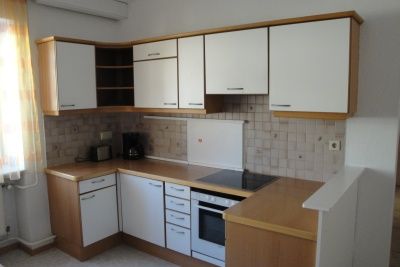 Kis konyha fehér szekrényekkel, tűzhely és kávéfőző.