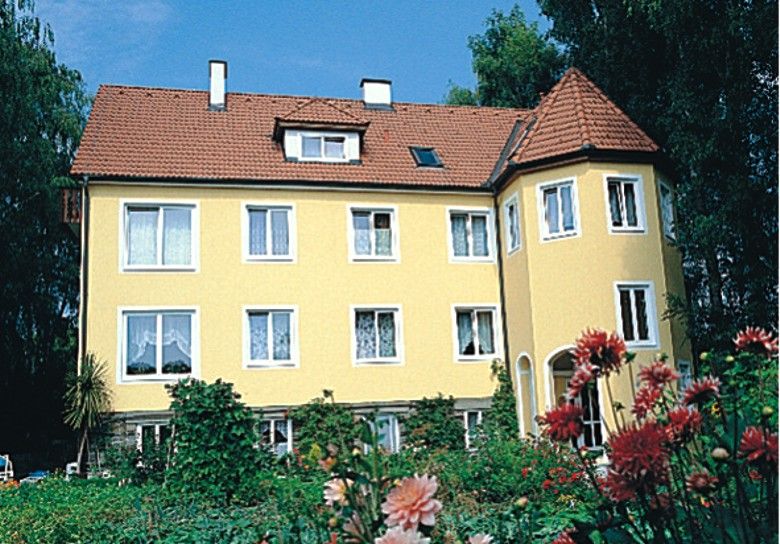 Sárga ház piros tetővel és kerttel az előtérben.