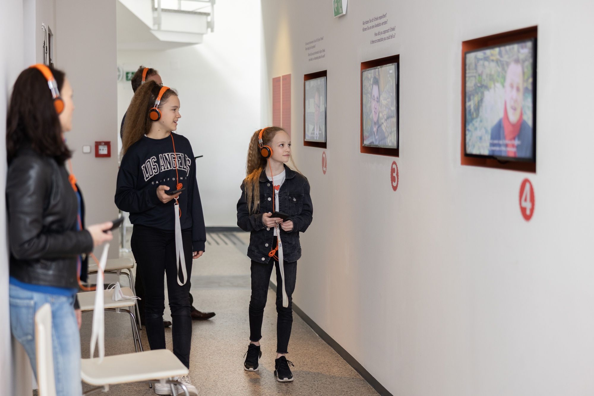 A látogatók fejhallgatóval nézik a képernyőket egy múzeumban.