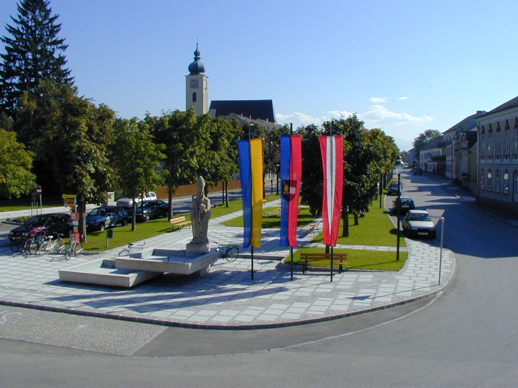 Ruprechtshofeni tér templommal, szobrokkal és zászlókkal.