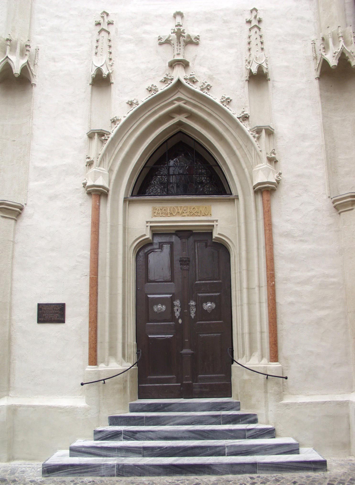 A Bürgerspitalskirche bejárata gótikus portállal és faajtóval.